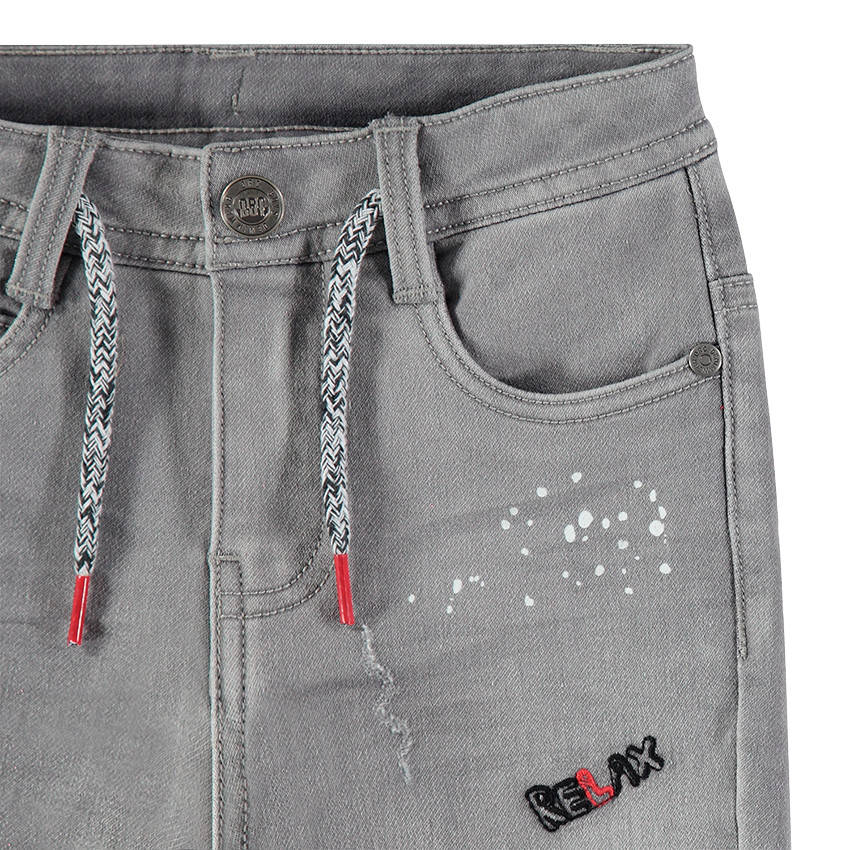 Jeans effet used avec taches printées et badges patchés 