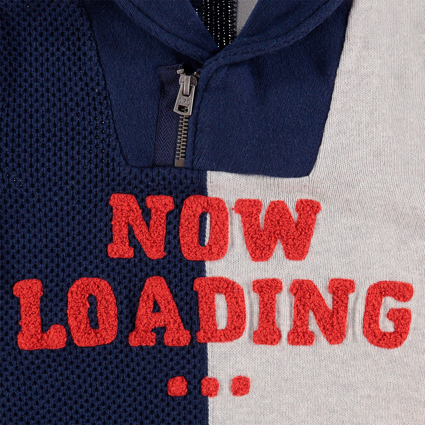 Pull en tricot bicolore avec col zippé et inscription en bouclette 